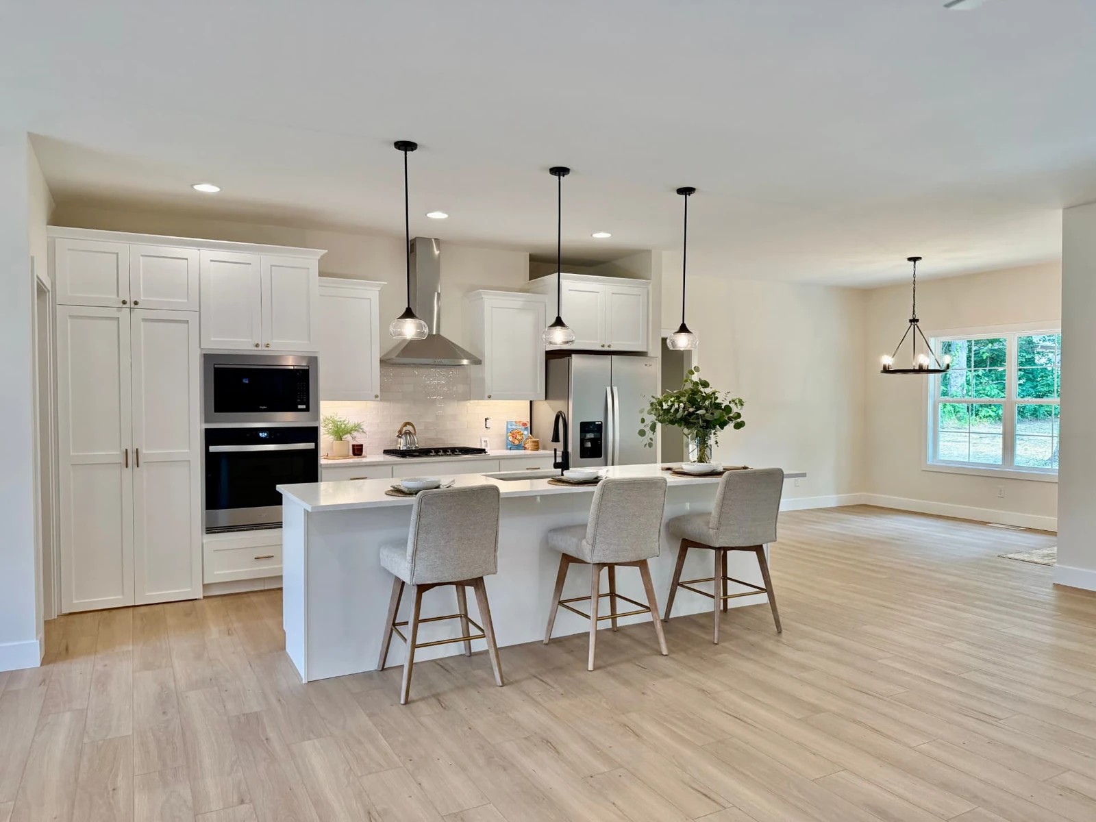 Sterchi Homes kitchen with white cabinetry, large island, pendant lights, and a concealed walk-through pantry entrance.